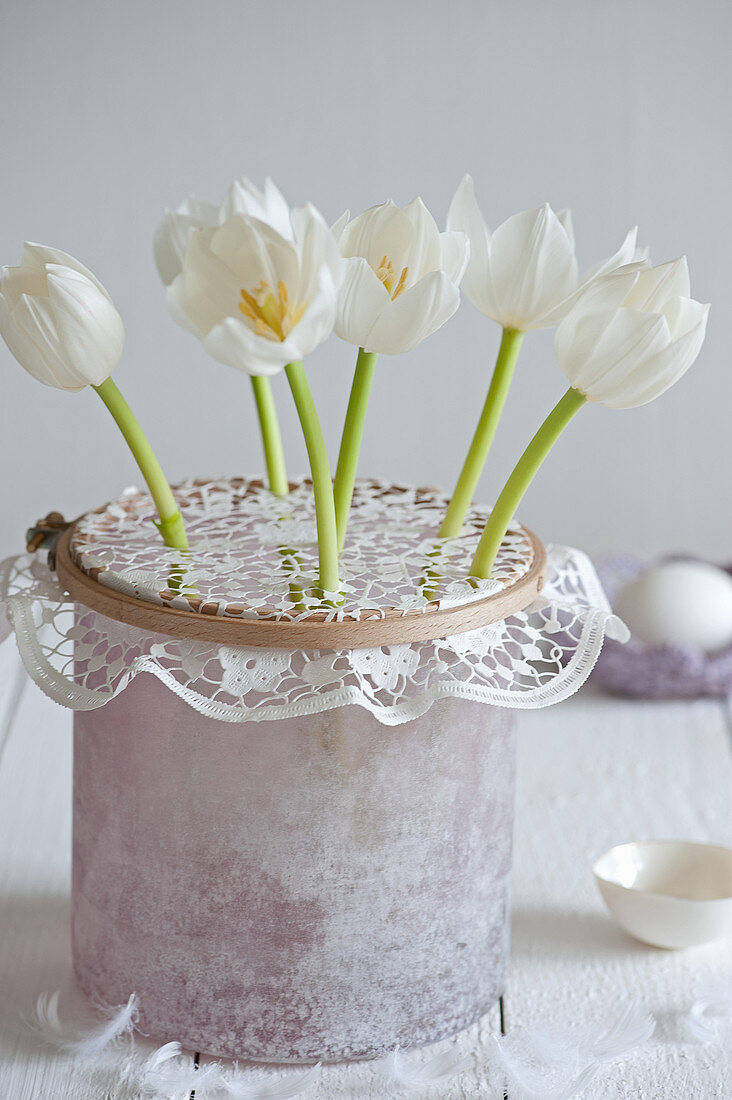 Weiße Tulpen in Spitzendeckchen als Steckhilfe