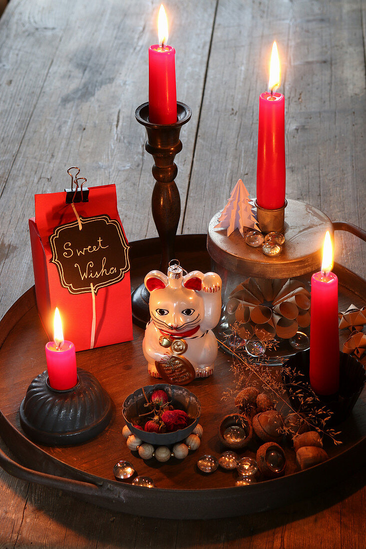 Winterdeko mit roten Kerzen und Katzenfigur auf einem Tablett