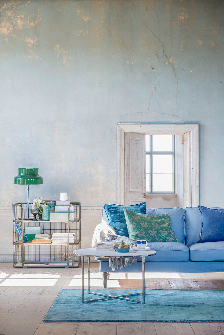Living room in shades of blue and green with distressed wall