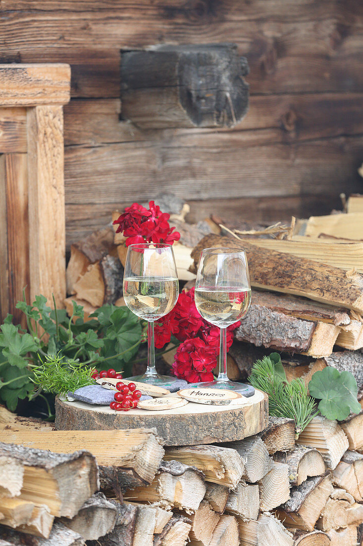 Two glasses of wine arranged with name tags on wooden discs outside Alpine cabin