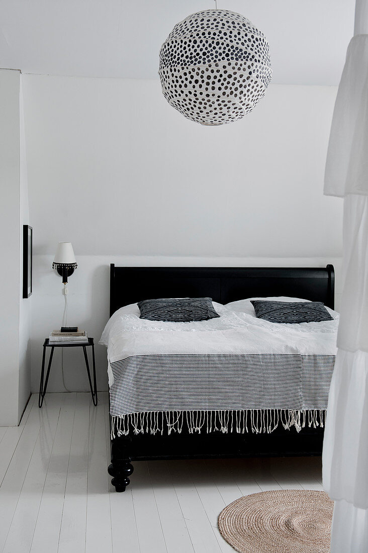 Polka-dot paper lampshade above black bed in bedroom