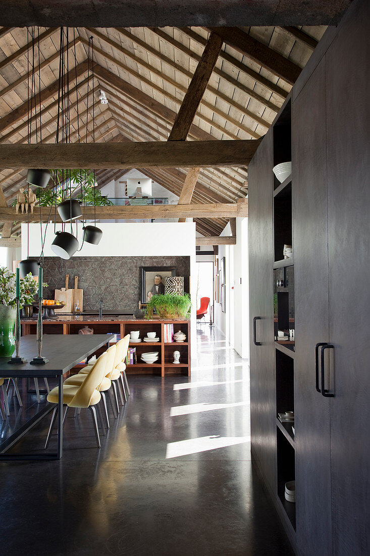 Rustic dining room with exposed roof beams and grey floor