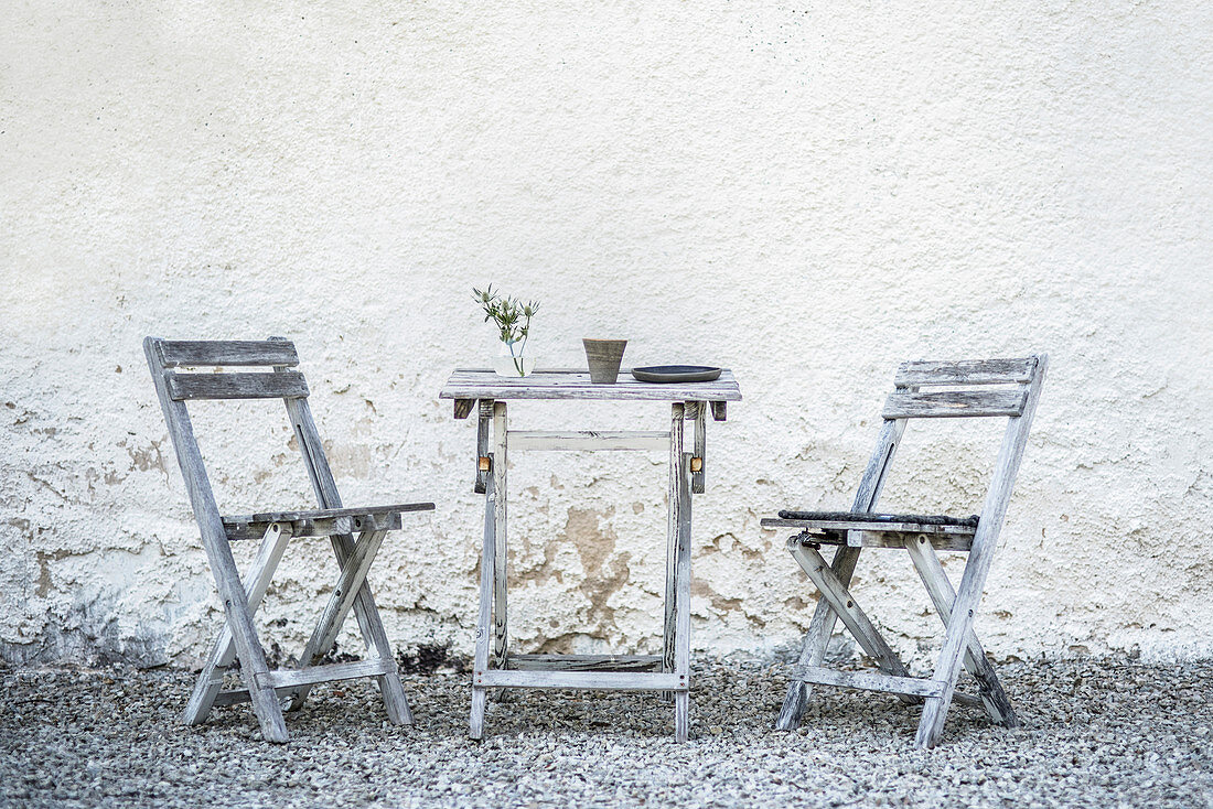 Rustic wooden table and chairs on gravel terrace