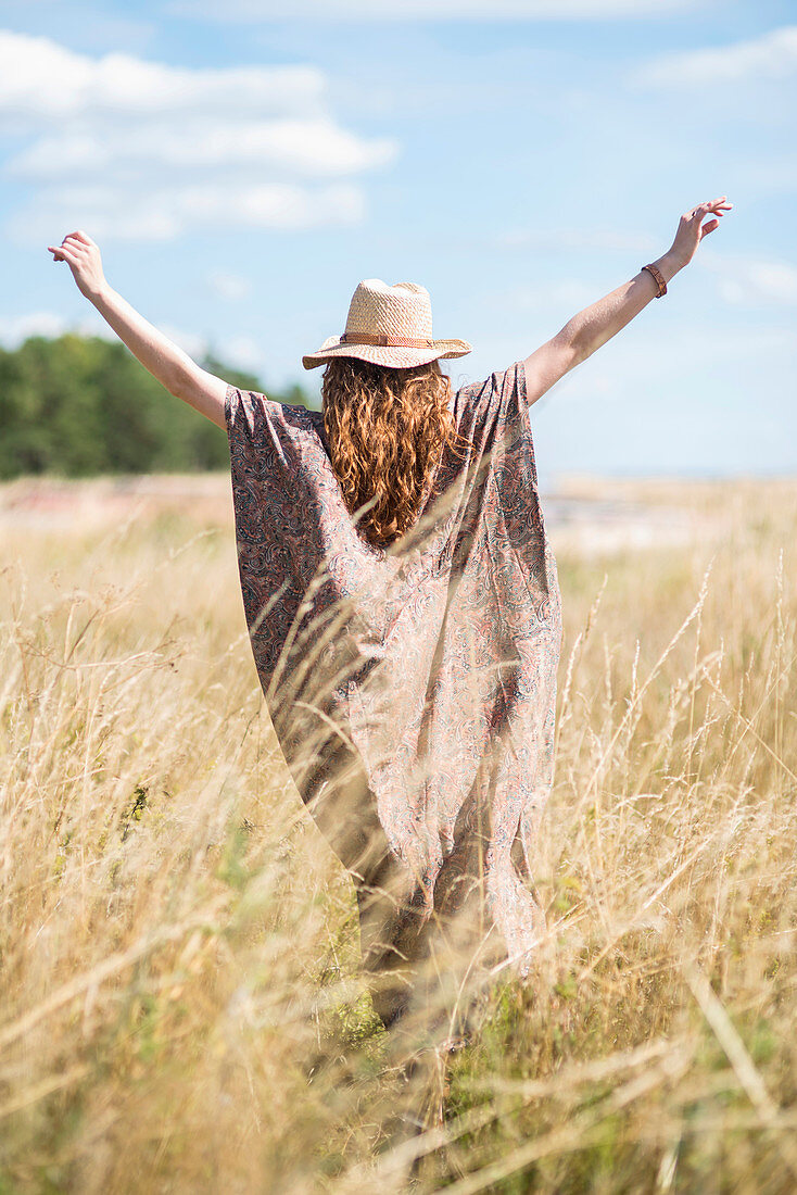 Woman with long hair wearing summer hat standing in field