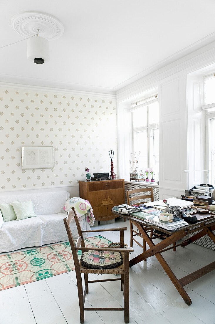 Stühle um alten Klapptisch im Wohnzimmer mit gepunkteter Tapete