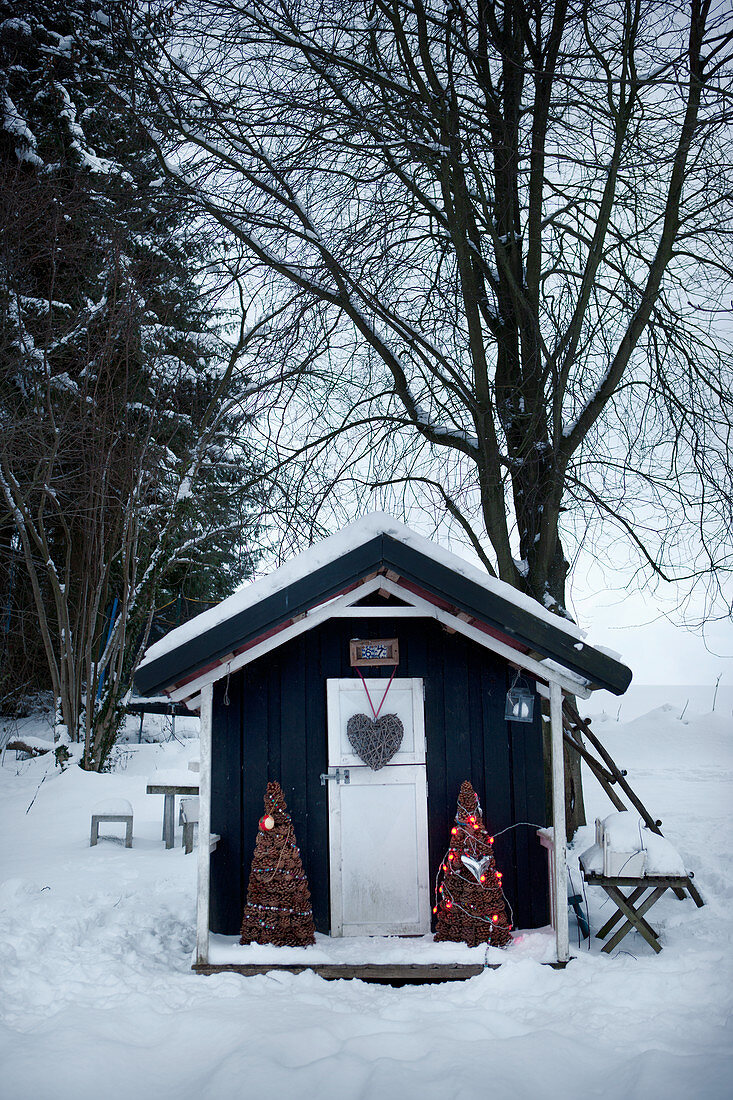 Weihnachtlich dekoriertes Gartenhäuschen im Schnee