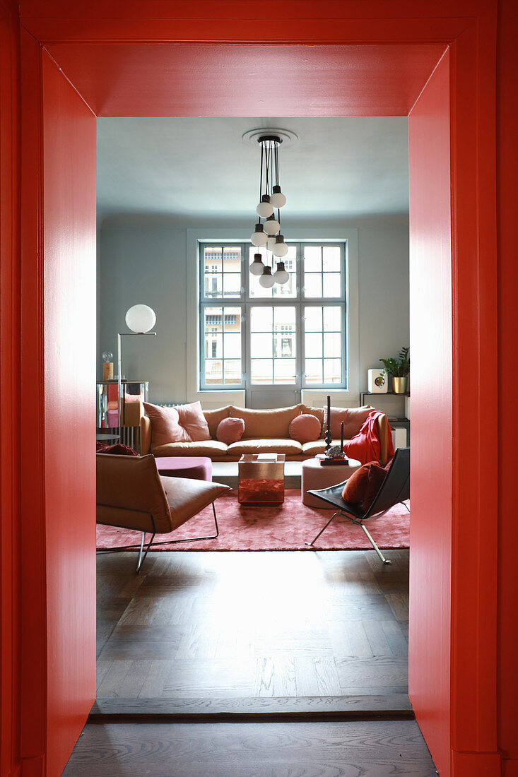 Blick durch rote Türzarge ins Wohnzimmer in gedeckten Farben
