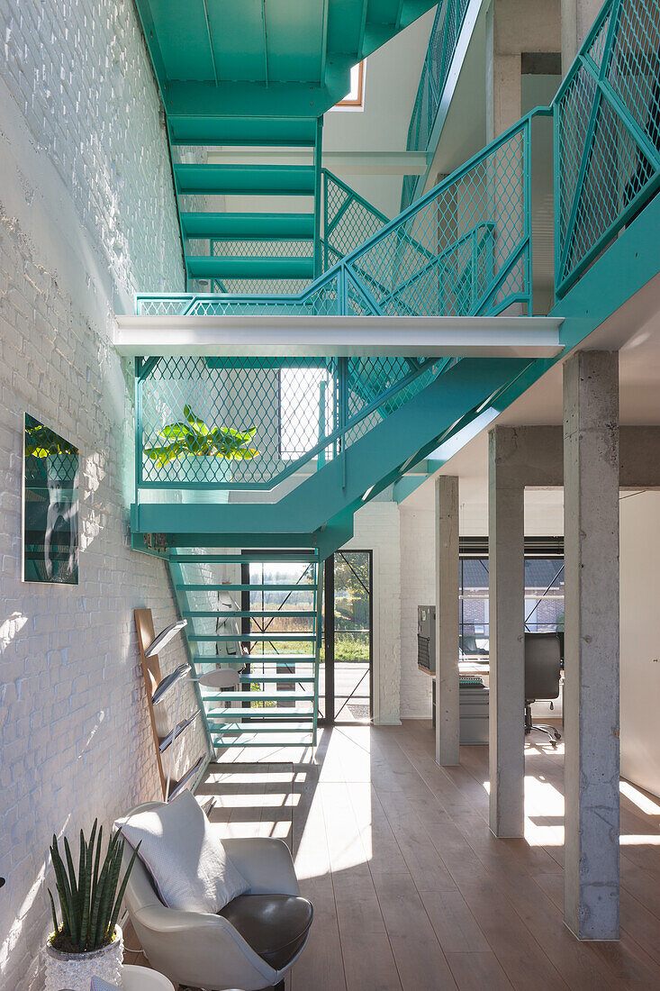 Bright living room with turquoise-coloured metal staircase and white brick walls