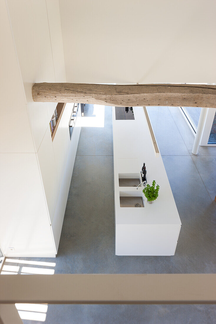Modern kitchen island with concrete floor and exposed wooden beams viewed from above