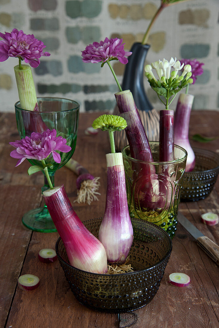 Chrysanthemums and bouvardia in hollowed-out spring onions used as vases
