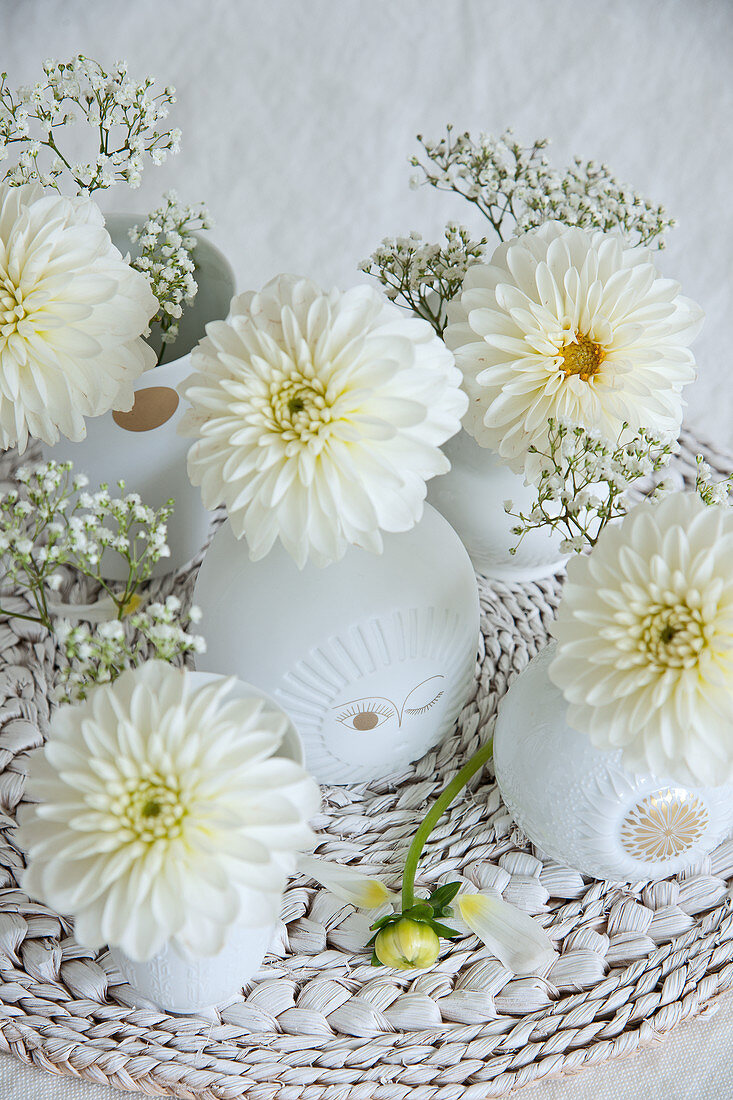 Dahlienblüten und Schleierkraut in weißen Vasen