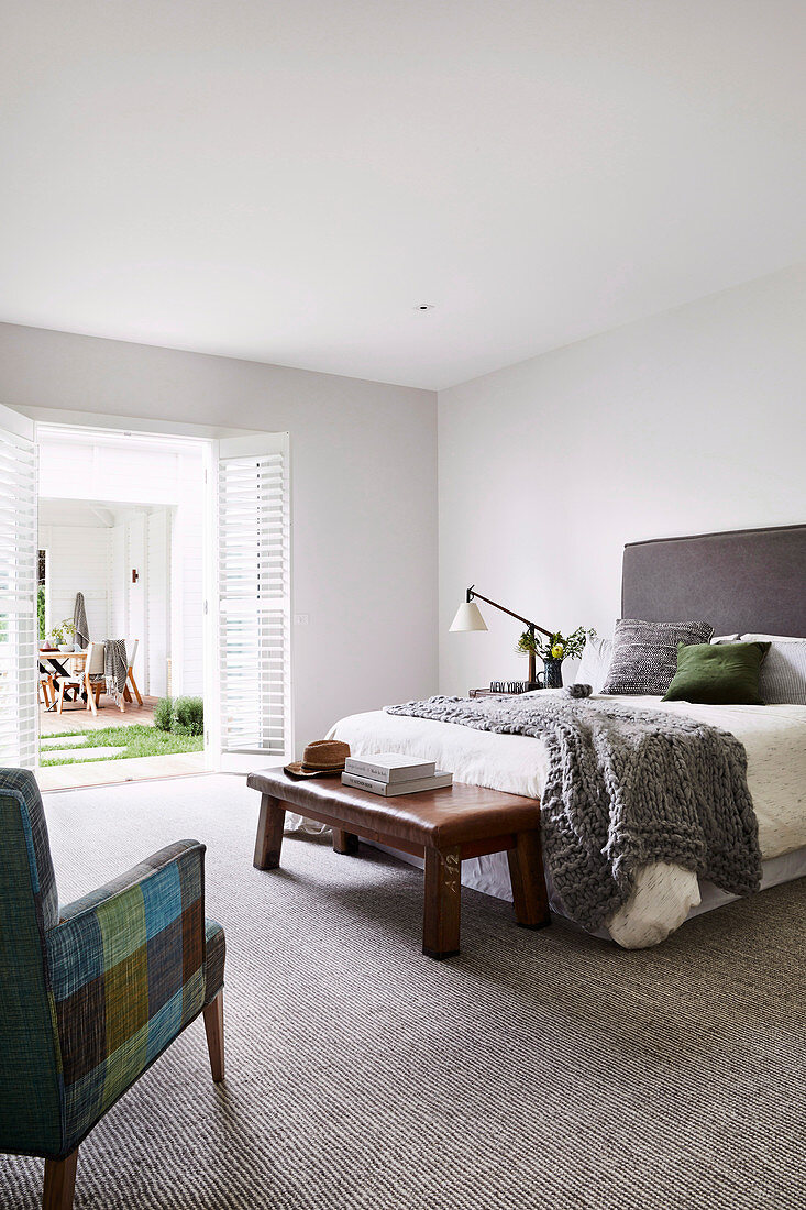 Schlichtes Schlafzimmer mit grauem Teppichboden und Gartenzugang