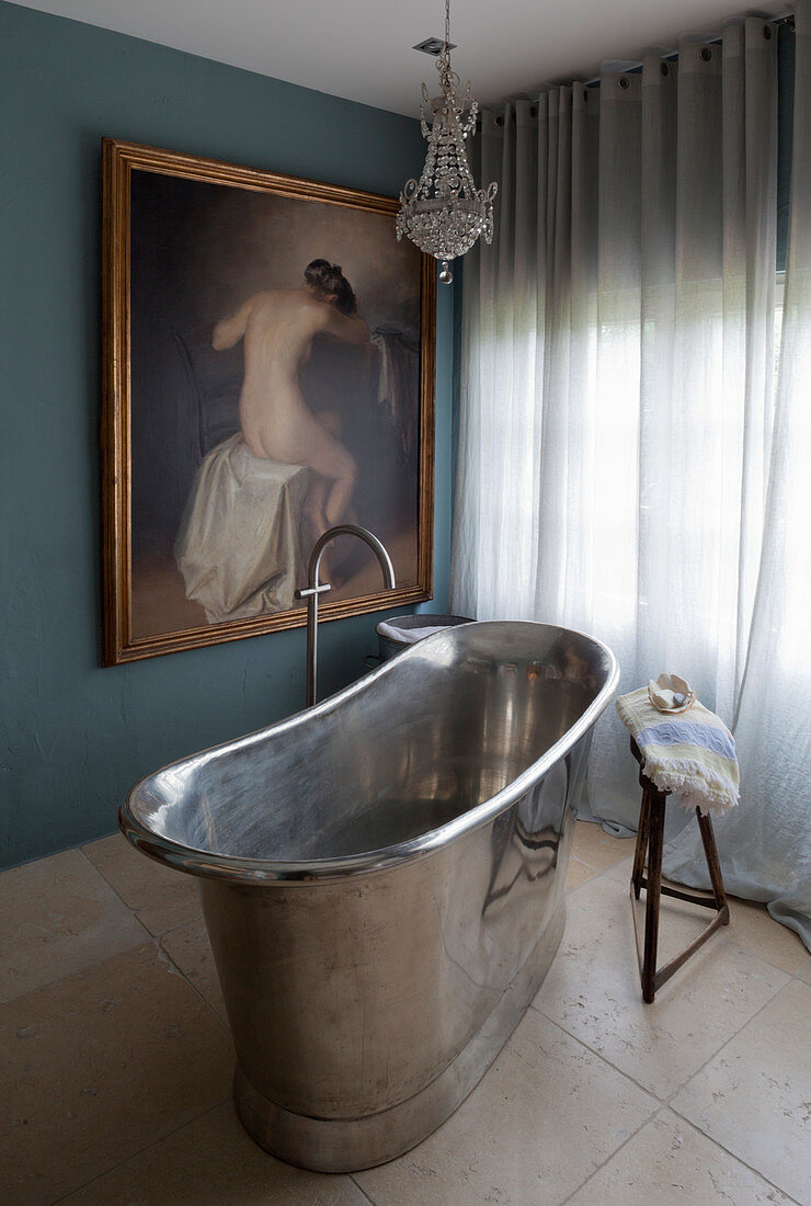 Freestanding, metal bathtub and classic painting in bathroom