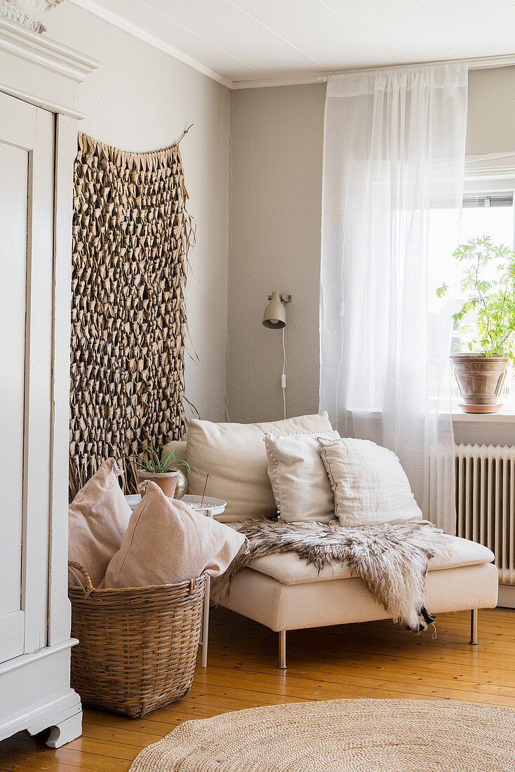 Sessel mit Fell vorm Wandbehang im Wohnzimmer im Boho-Stil