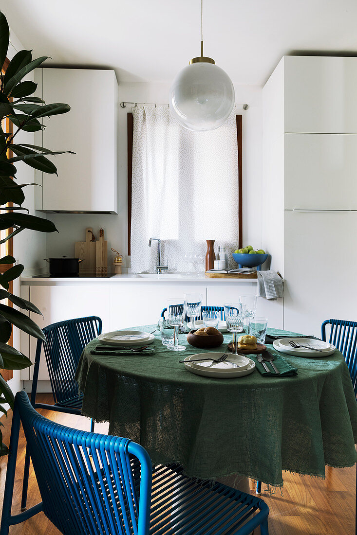 Gedeckter Tisch mit blauen Stühlen in kleiner Wohnküche