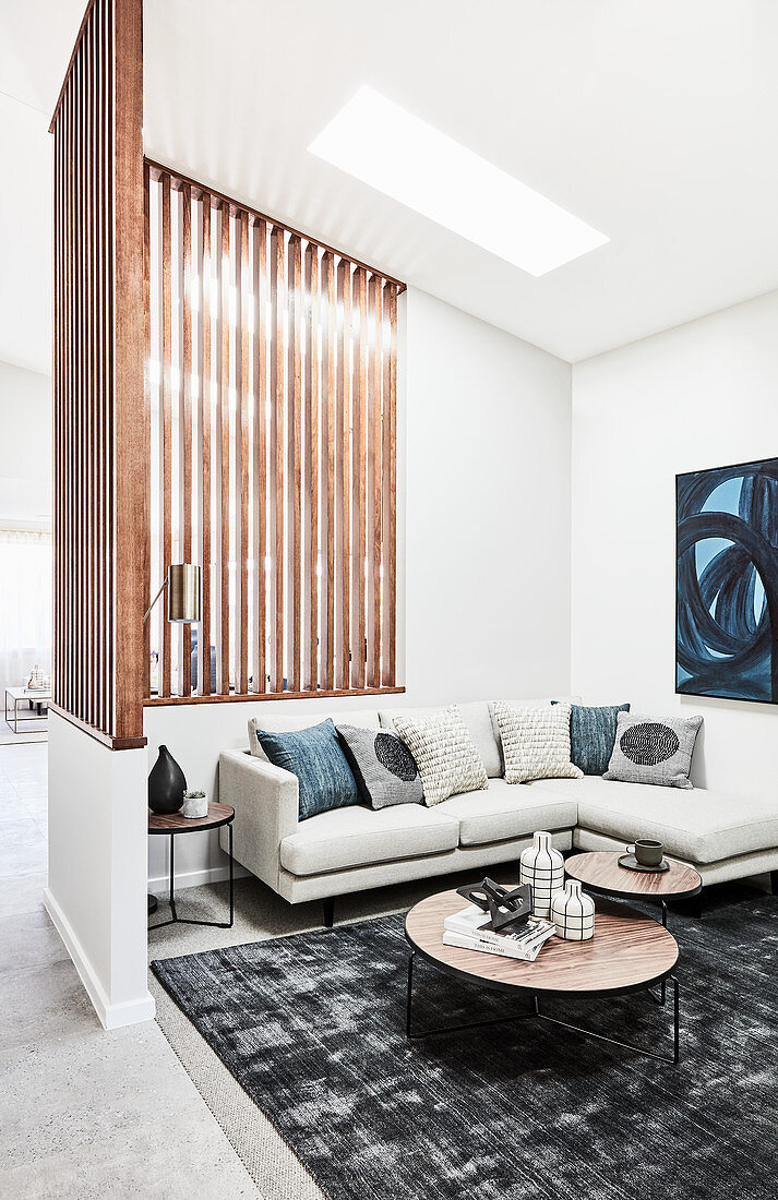 Pale corner sofa and set of coffee table in lounge area with slatted wooden partition