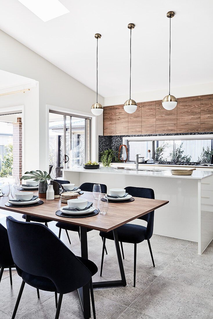 Gedeckter Esstisch mit eleganten Stühlen vor Kücheninsel in offenem Wohnraum