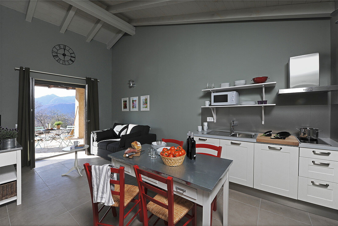 Tisch mit Stühlen in der Küche mit grauen Wänden und Terrassenzugang