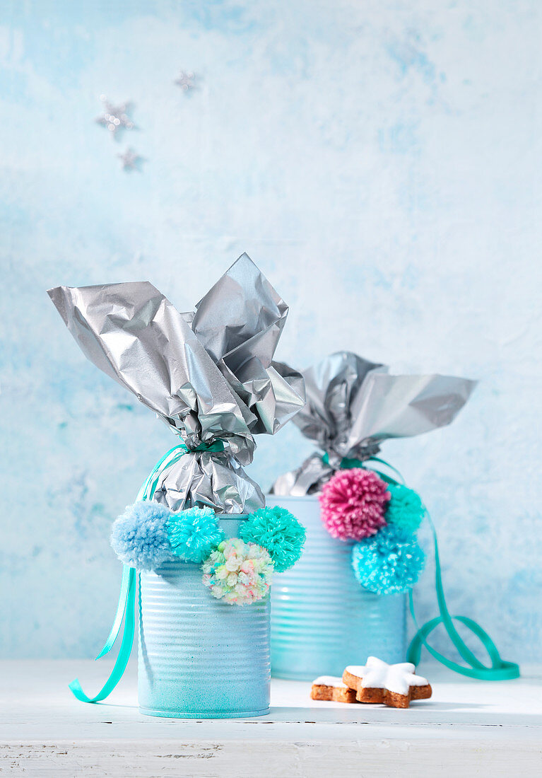 Handmade, festive gift containers made from tin cans decorate with pompoms