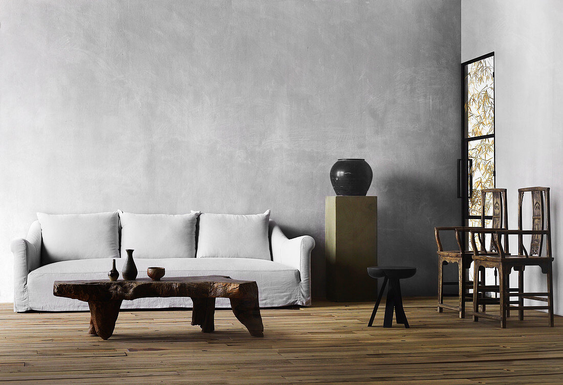 Massiver Couchtisch, Polstersofa, Stele mit Vase und zwei Stühle im Wohnzimmer mit grauen Wänden