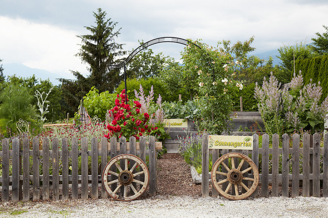 Alte Wagenräder am Eingang zum Garten mit Rosenbogen