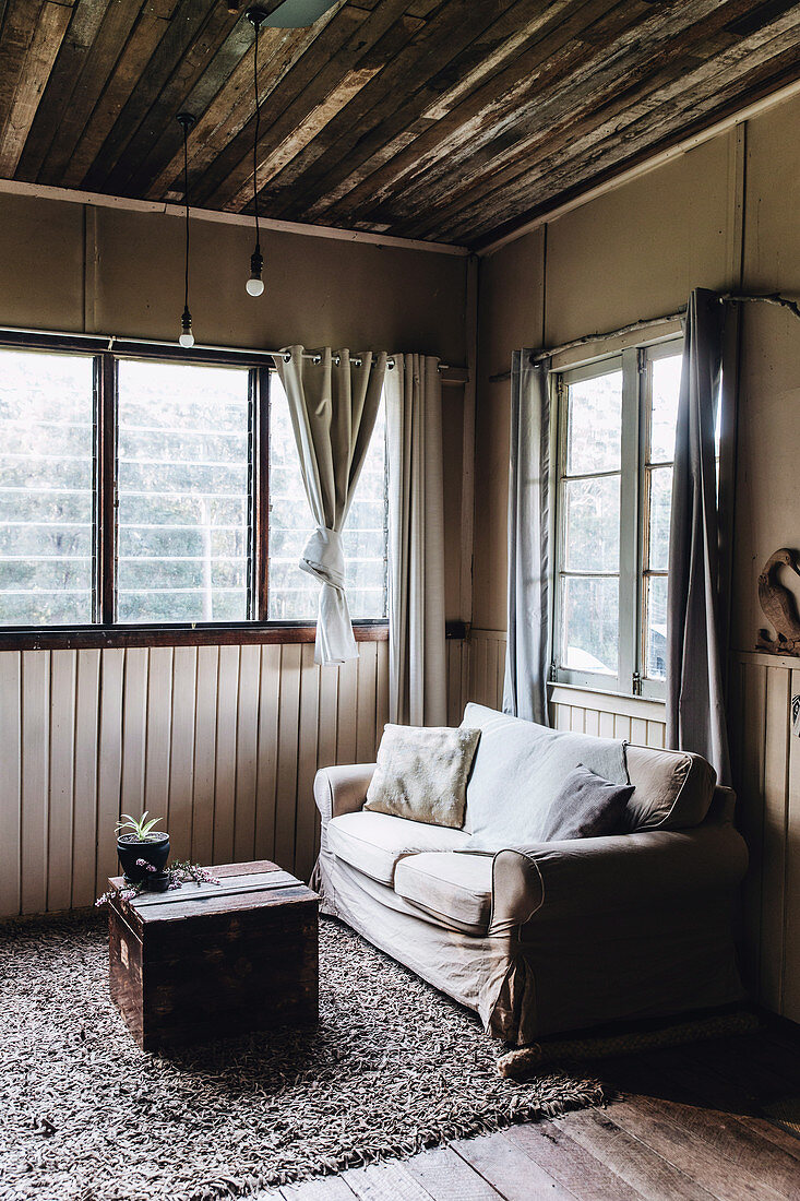 Wohnzimmer in Brauntönen mit rustikaler Holzdecke