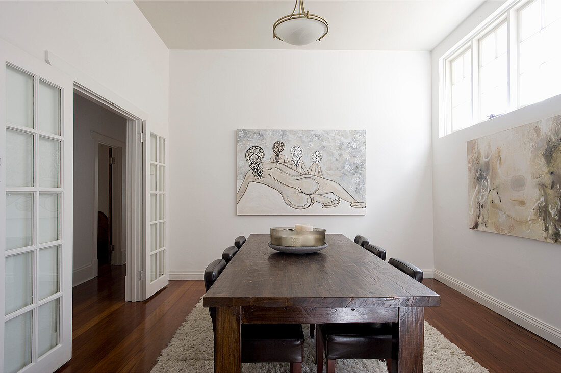 Rustikaler Holztisch mit Lederstühlen und moderne Kunstwerke an der Wand im Speisesaal