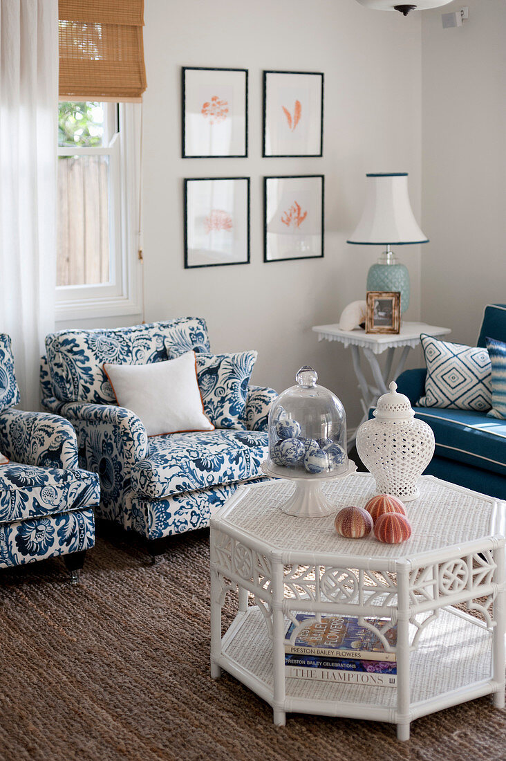 Weißer Rattantisch, blau-weiße Polstersessel und Beistelltisch im Wohnzimmer