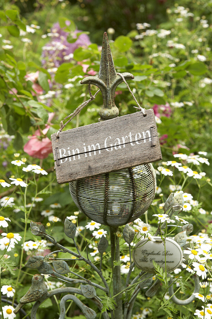 Ornamental stake with sign reading 'Bin im Garten' (I'm in the garden) in flowerbed