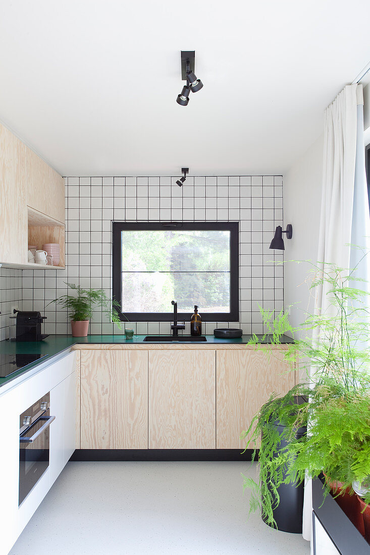 Kitchen with white wall tiles and pale wooden cupboards