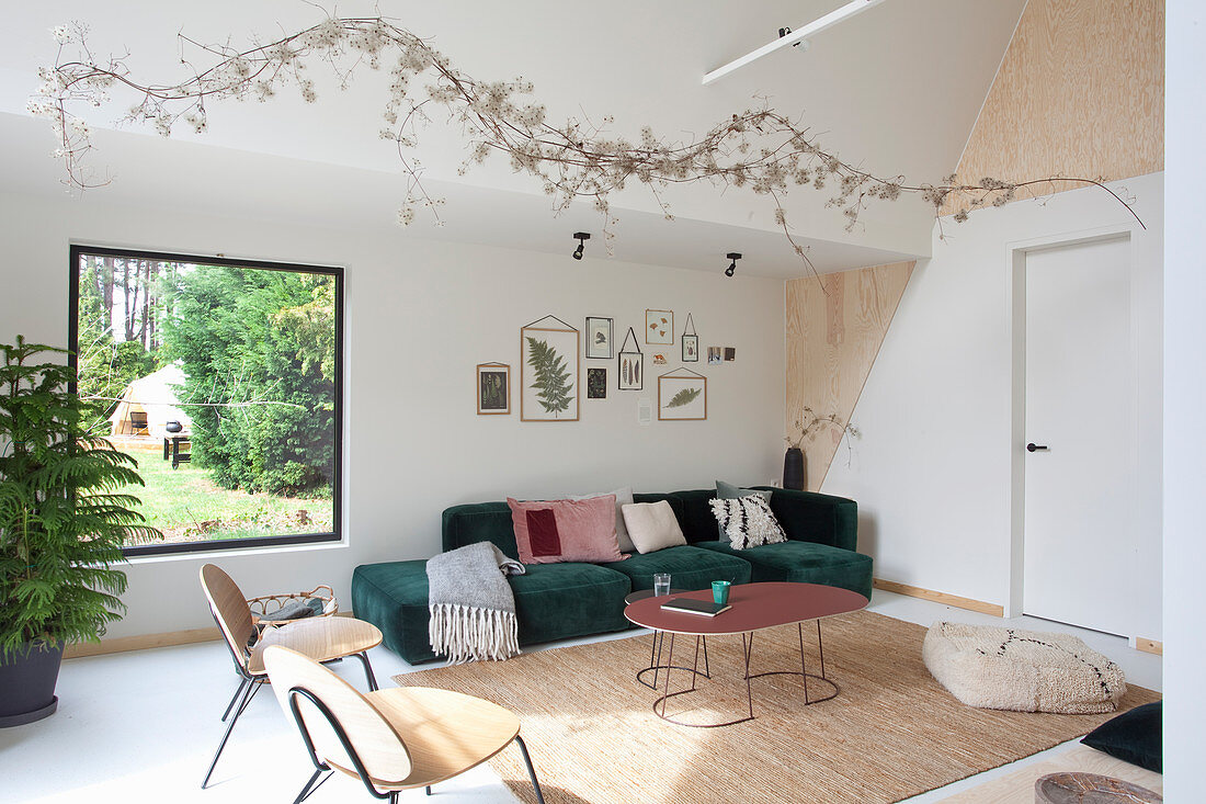 Dunkelgrünes Recamiere in Wohnzimmer mit Giebeldach und Holzelementen zur Wandgestaltung