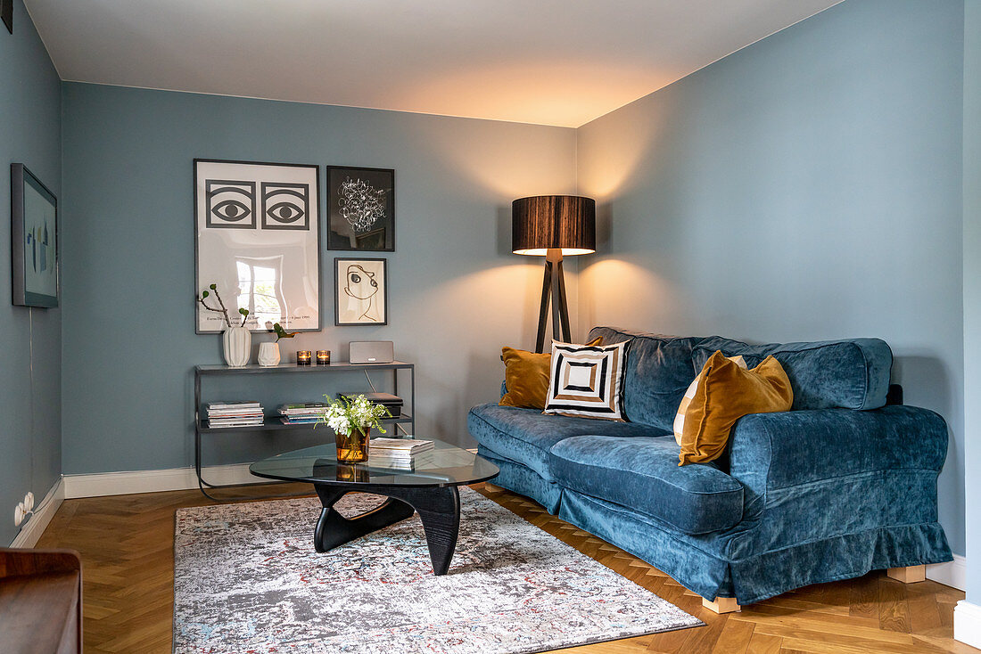 Blue velvet sofa, standard lamp and coffee table in room with blue walls