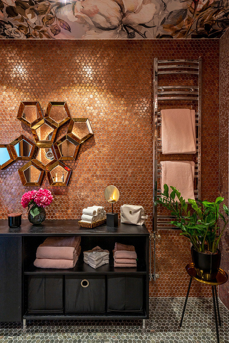 Sideboard mit Handtüchern, Designerspiegel an Mosaikfliesenwand und Handtuchhalter im Bad
