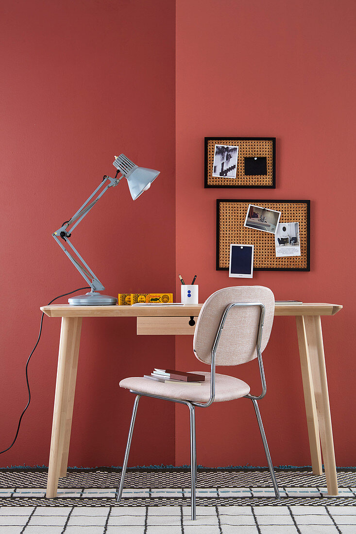 DIY-Pinnwand aus Wiener Geflecht an rot gestrichener Wand, davor Schreibtisch und Stuhl