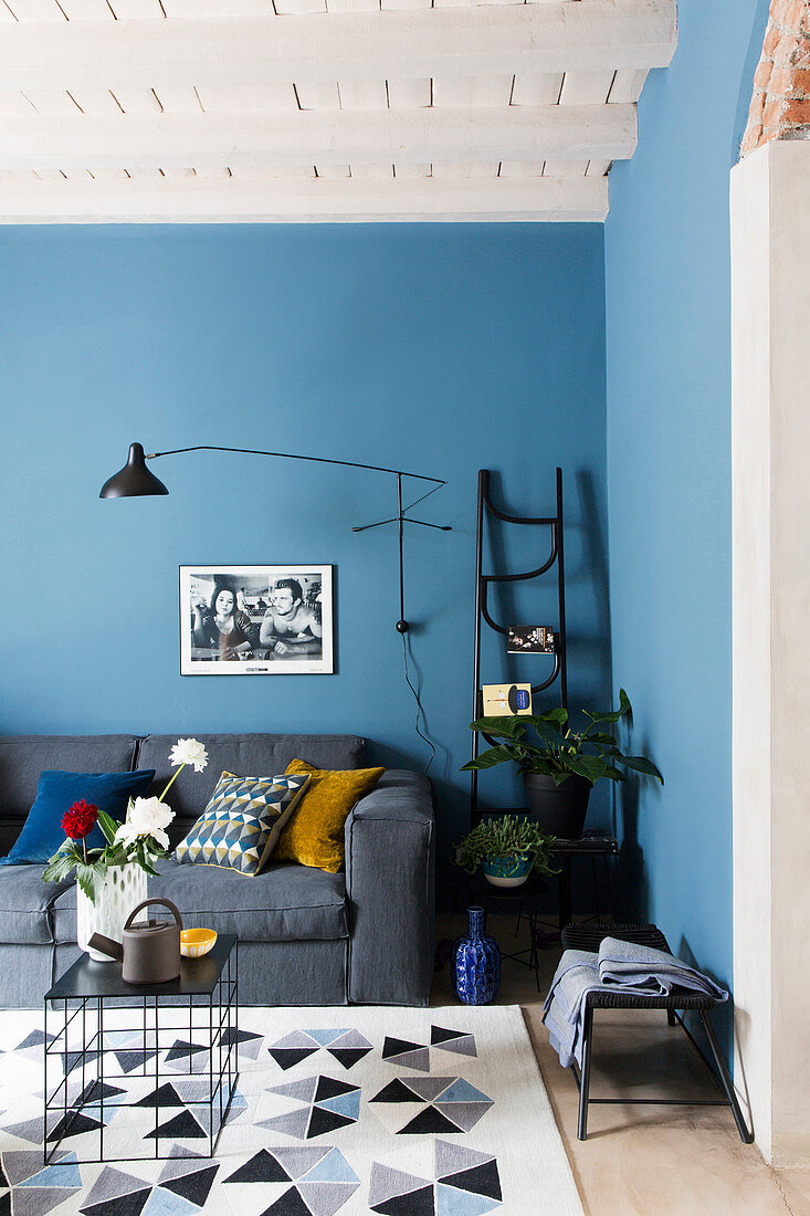 Grey sofa in living room with blue wall and white wood-beamed ceiling