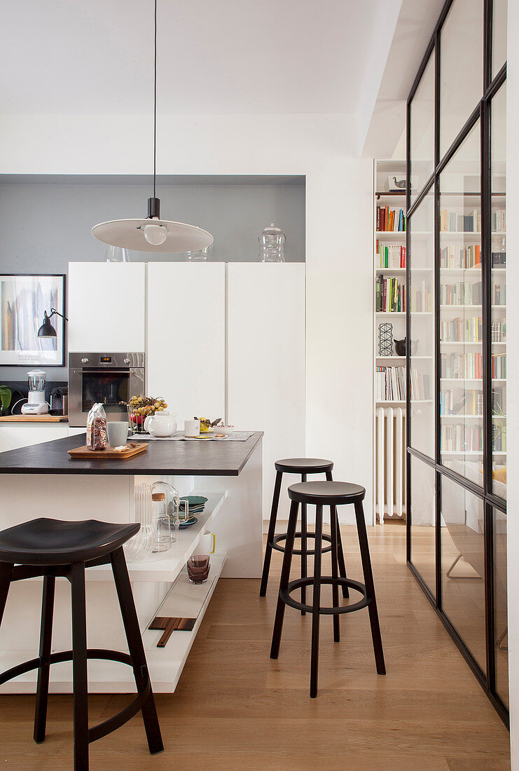 Black-and-white, contemporary kitchen separated from living area by interior glass wall