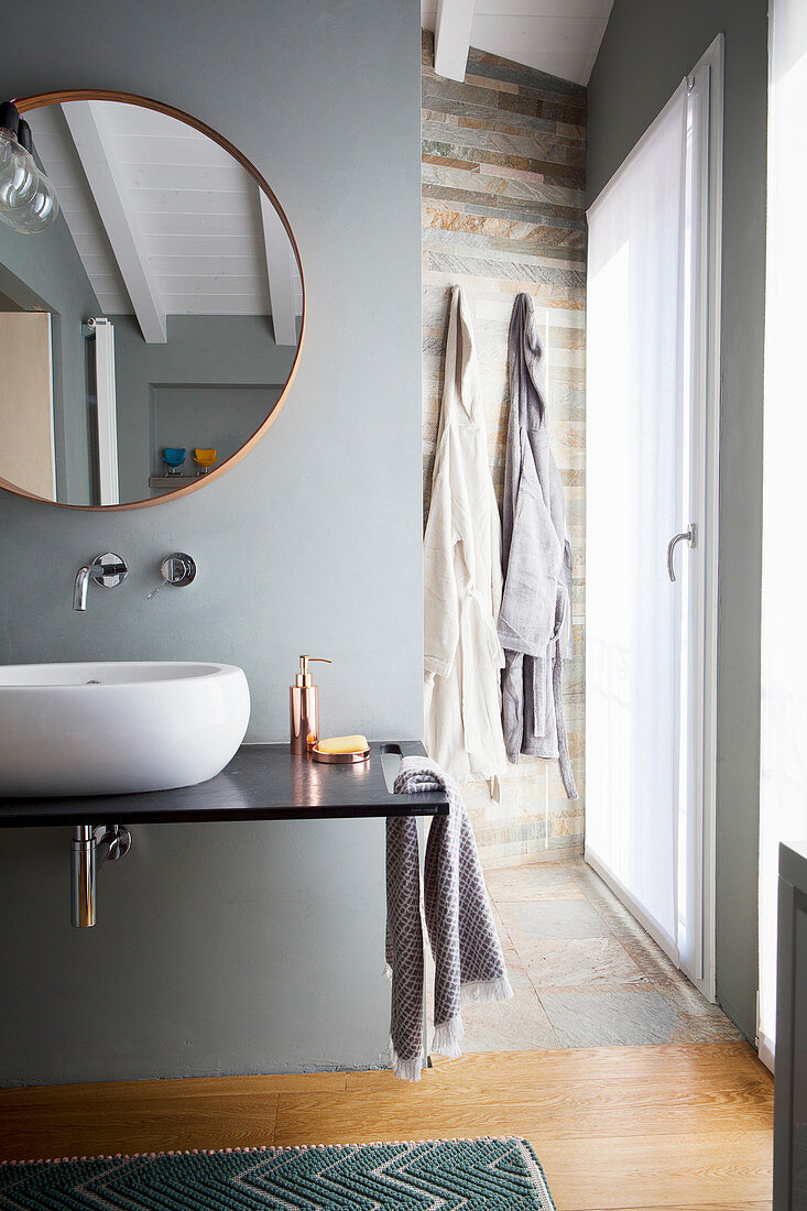 Badezimmer mit rundem Spiegel über modernem Waschtisch