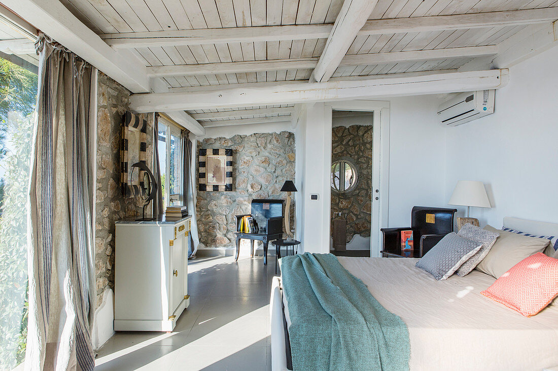 Elegantes Schlafzimmer im mediterranen Stil mit Natursteinwänden