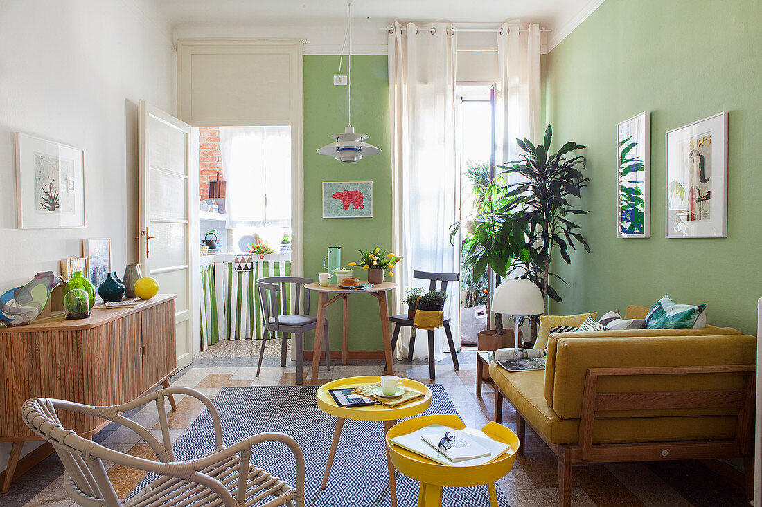 Gelbes Sofa und Beistelltischchen in hellem Wohnraum mit grünen Wänden