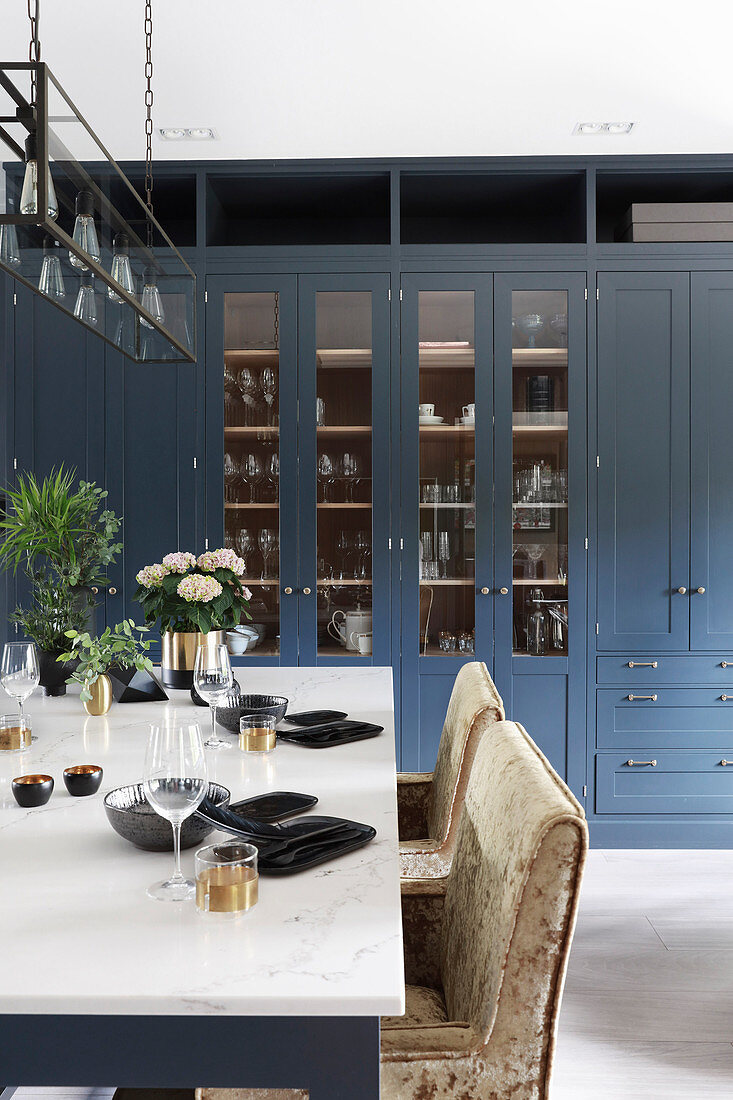 Blue cabinets with glass doors and set table in kitchen-dining room