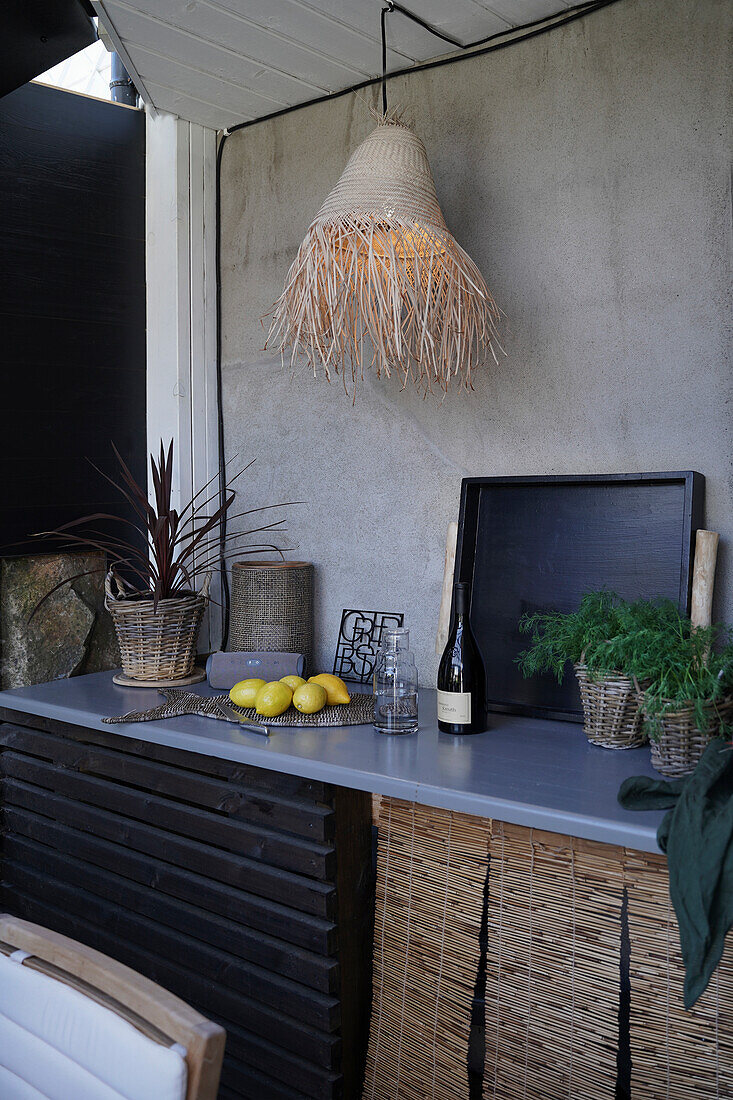 Raffia lampshade above worksurface of outdoor kitchen