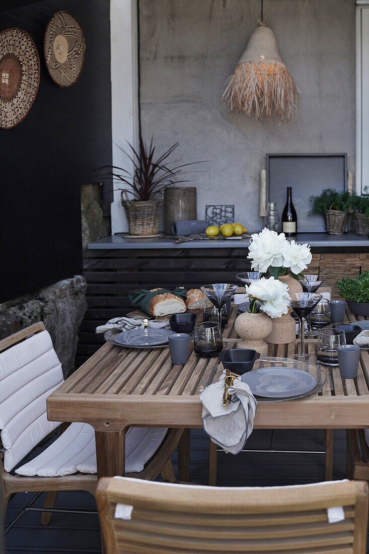 Gedeckter Tisch in Naturtönen auf der Terrasse mit exotischer Deko