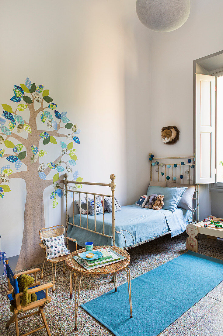 Kinderzimmer in Altbauwohnung mit nostalgischem Metallbett und gemaltem Baummotiv