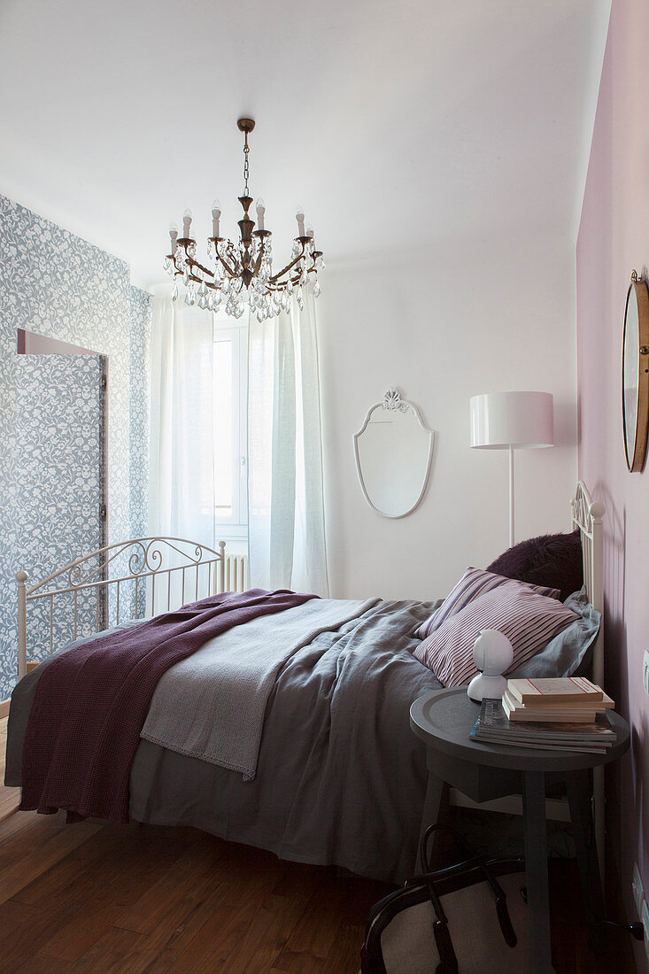 Double bed against pink bedroom wall and ensuite bathroom behind wall with patterned wallpaper