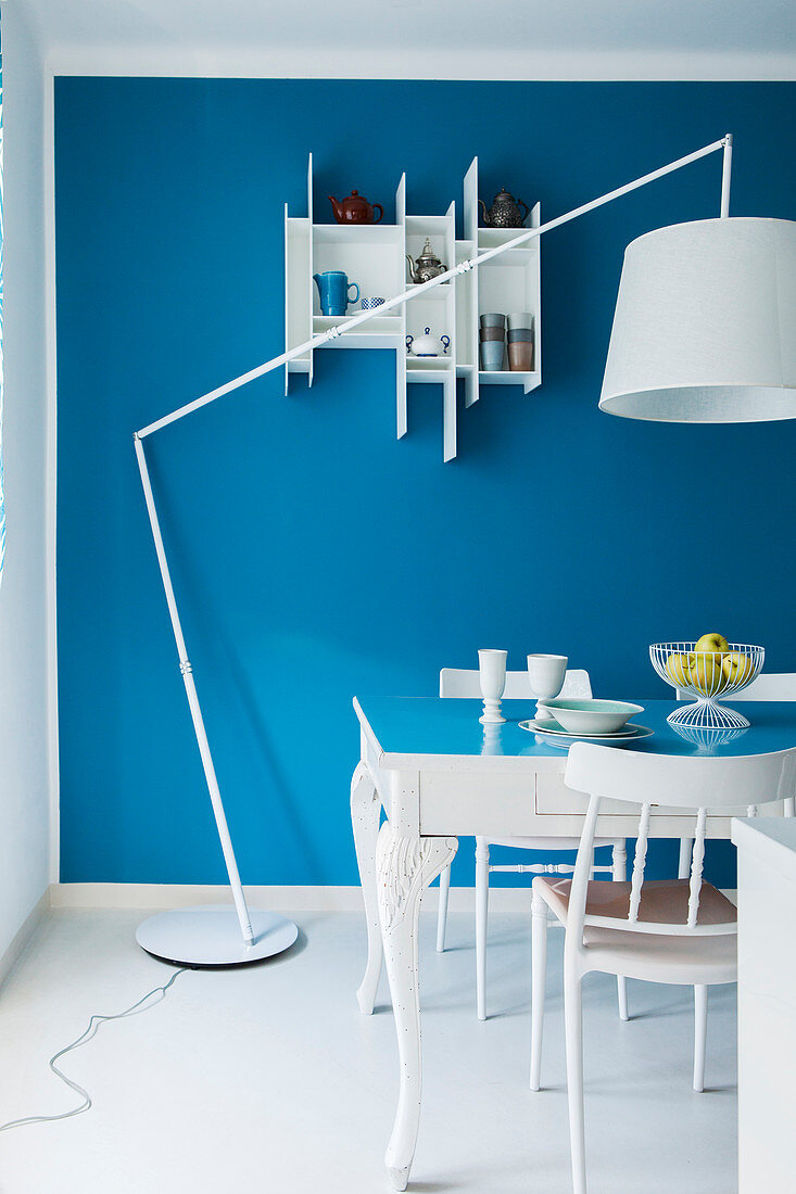 Blau-weißer Essbereich mit Tisch, Stühlen, Stehleuchte und Wandregal