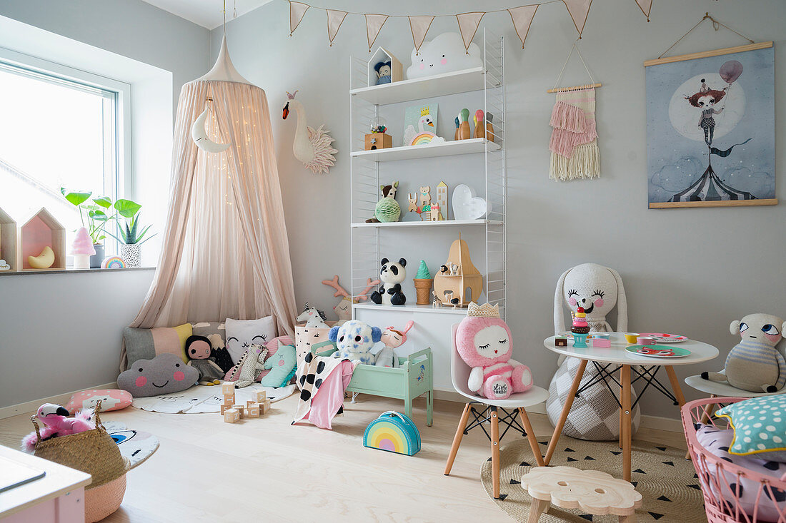 Canopy, table and small chairs in play area of girl's bedroom in pastel shades