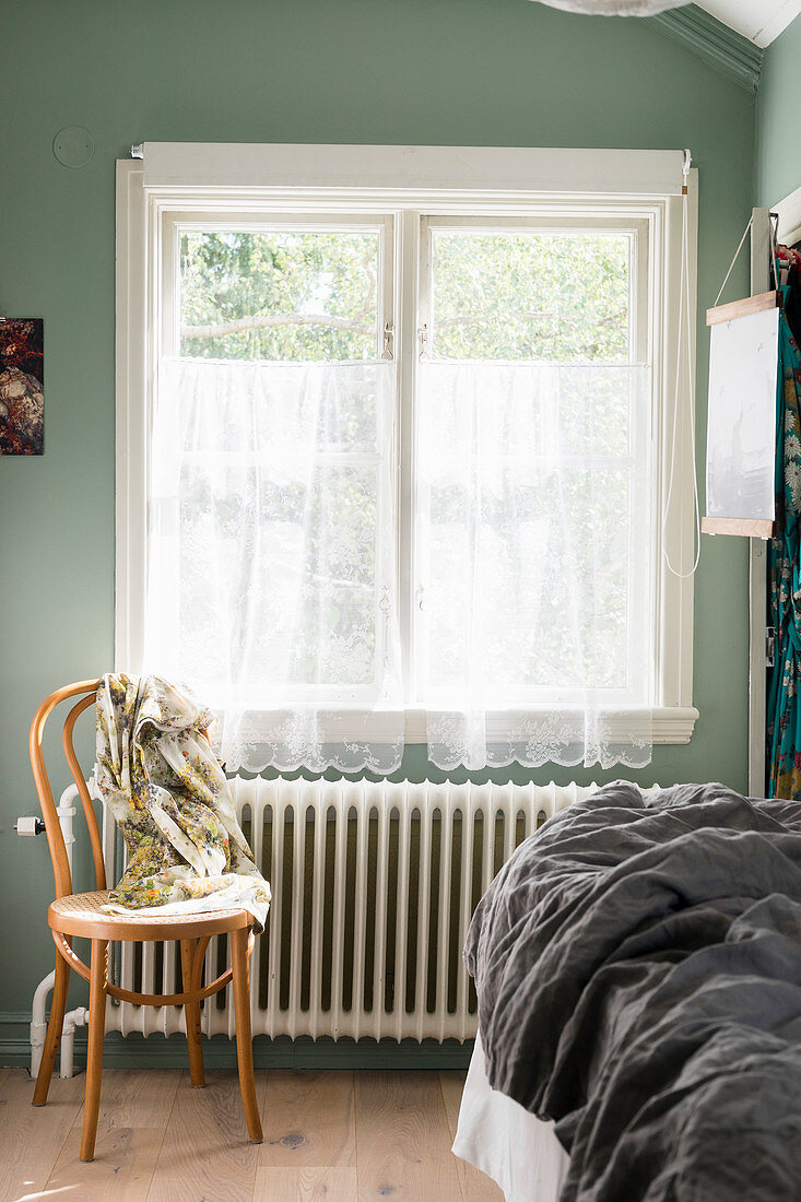 Bistro chair below window with net curtains in bedroom