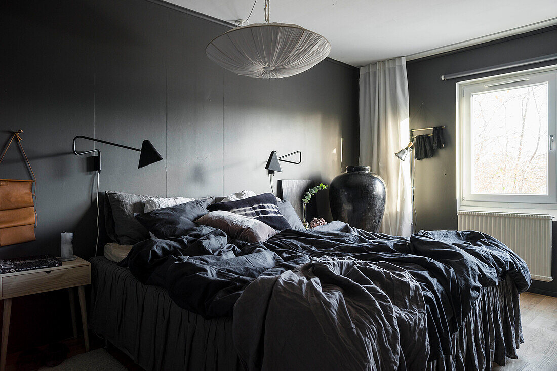 Bed with valance and dark bed linen against grey wall