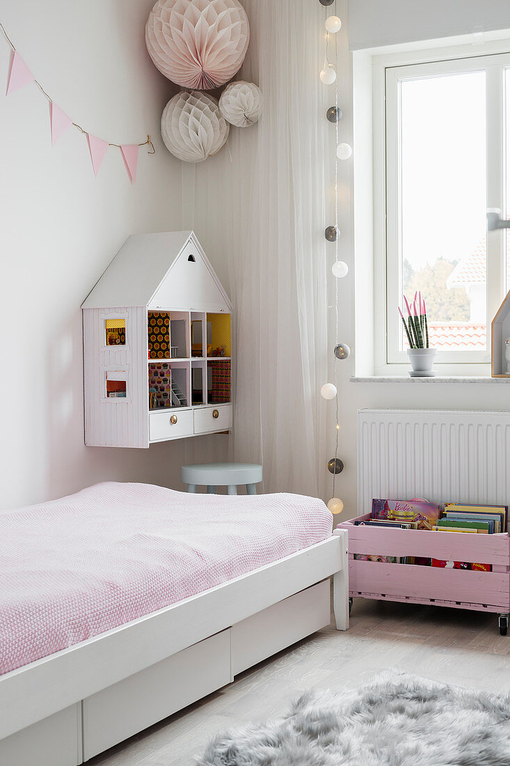 Mädchenzimmer mit aufgehängtem Puppenhaus neben Bett in Spielecke