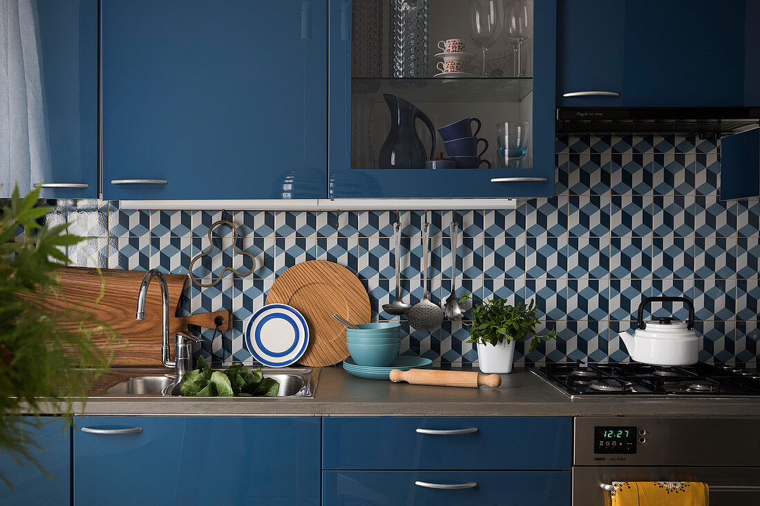 Fitted kitchen with blue fronts and tiled splashback with graphic pattern